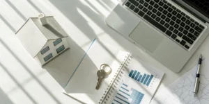 Real estate bookkeeping services with a house model, financial charts, and a laptop on a desk.